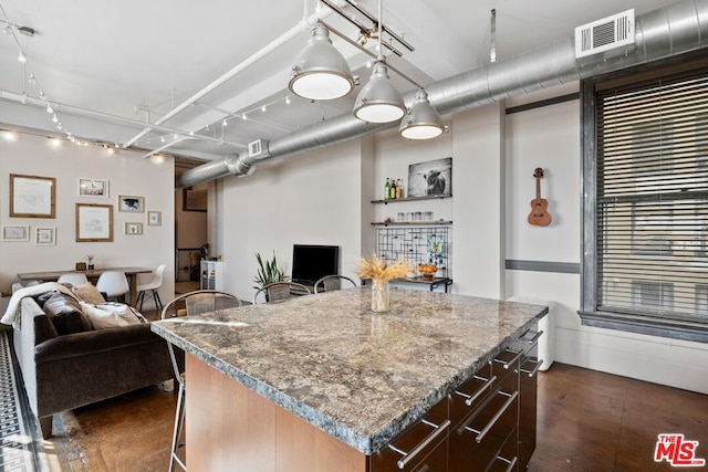 kitchen with a kitchen island, light stone countertops, and a breakfast bar