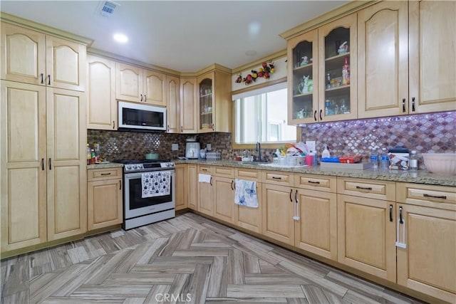 kitchen featuring tasteful backsplash, light brown cabinets, electric range, light parquet flooring, and light stone counters