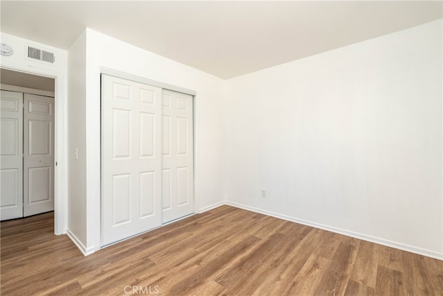 unfurnished bedroom featuring a closet and hardwood / wood-style floors