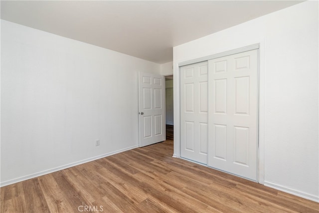 unfurnished bedroom with light hardwood / wood-style flooring and a closet