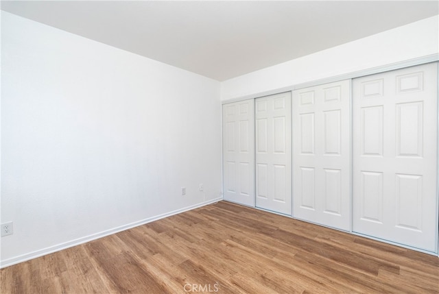 unfurnished bedroom with wood-type flooring and a closet