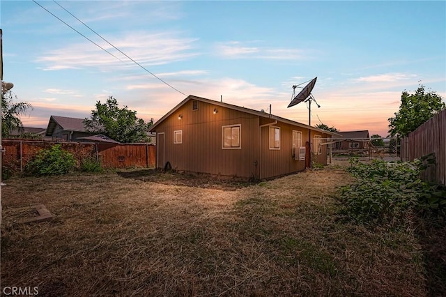 property exterior at dusk featuring a lawn