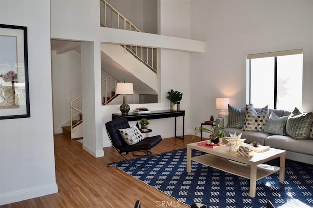 living room with wood-type flooring and a towering ceiling