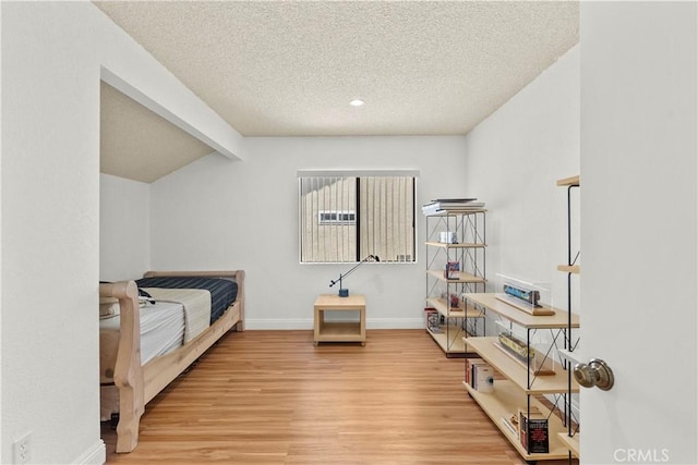 bedroom with wood finished floors, a textured ceiling, baseboards, and lofted ceiling with beams