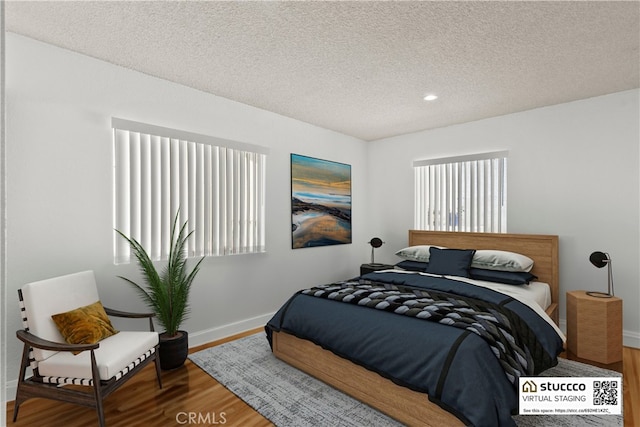 bedroom with baseboards, recessed lighting, wood finished floors, and a textured ceiling