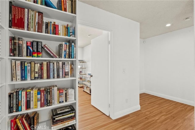 living area with baseboards, wood finished floors, and recessed lighting