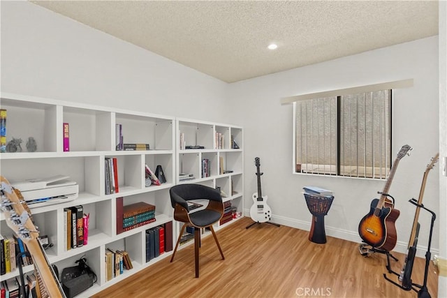 living area with baseboards, wood finished floors, a textured ceiling, and recessed lighting