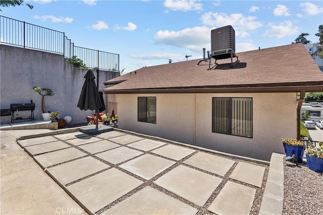 back of house featuring a patio area, roof with shingles, cooling unit, and stucco siding