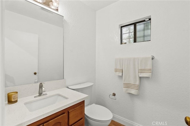 bathroom featuring vanity, baseboards, toilet, and wood finished floors