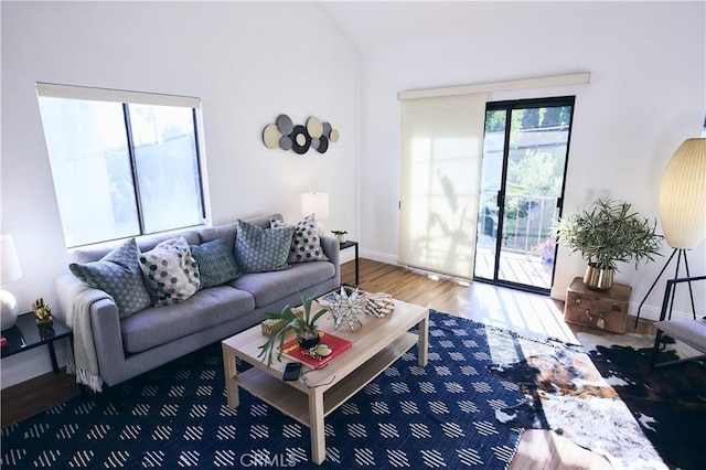 living area with baseboards, lofted ceiling, and wood finished floors