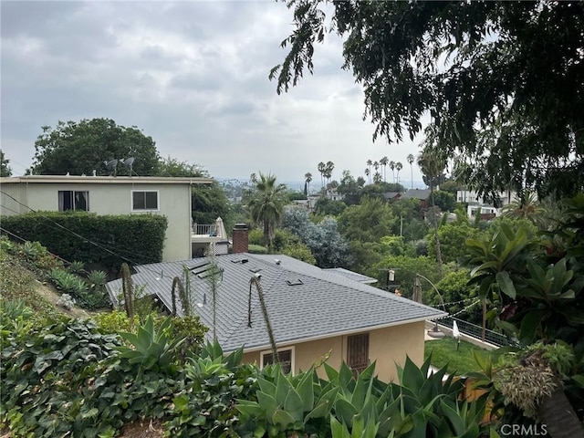 view of side of home with a chimney, a shingled roof, and stucco siding