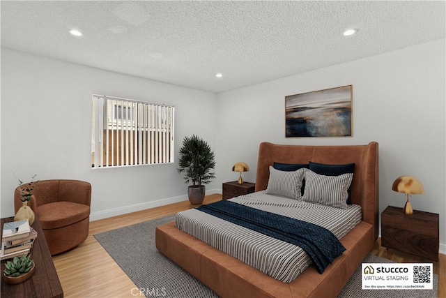 bedroom featuring baseboards, recessed lighting, wood finished floors, and a textured ceiling