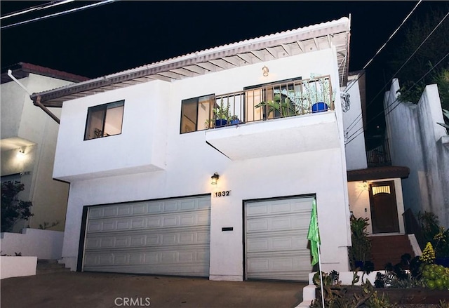 view of front of house with an attached garage, stucco siding, and a balcony