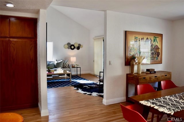 bedroom with light wood-style flooring, baseboards, and vaulted ceiling