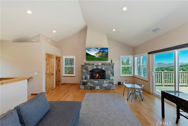 living room featuring a fireplace, light hardwood / wood-style floors, and high vaulted ceiling