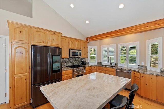 kitchen with sink, a center island, decorative backsplash, appliances with stainless steel finishes, and light wood-type flooring