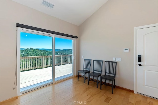 doorway to outside with a mountain view, light hardwood / wood-style floors, and lofted ceiling