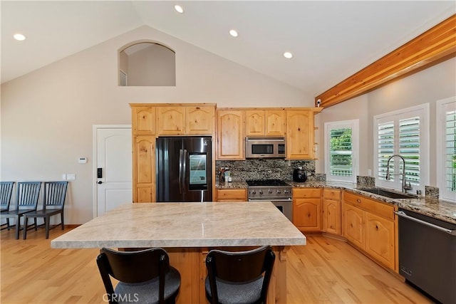 kitchen with high vaulted ceiling, a center island, appliances with stainless steel finishes, and light hardwood / wood-style flooring