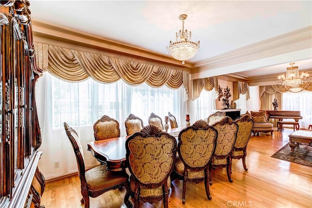 dining room with an inviting chandelier, light hardwood / wood-style flooring, and crown molding