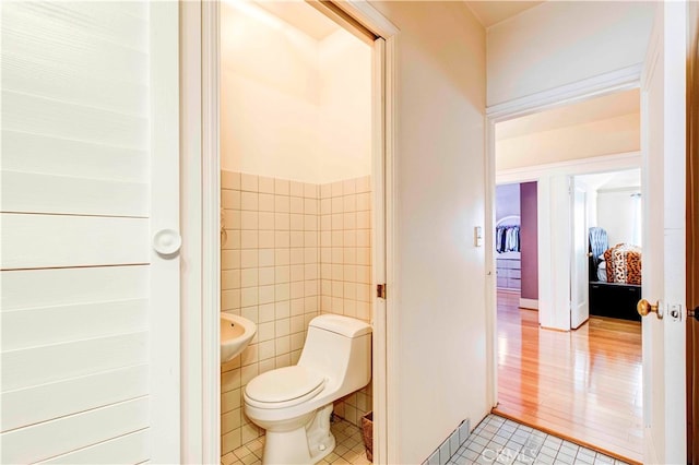 bathroom featuring hardwood / wood-style floors, tile walls, and toilet