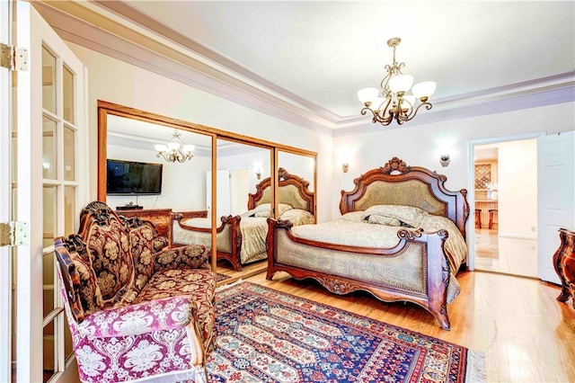 bedroom featuring crown molding, light hardwood / wood-style flooring, a closet, and a notable chandelier