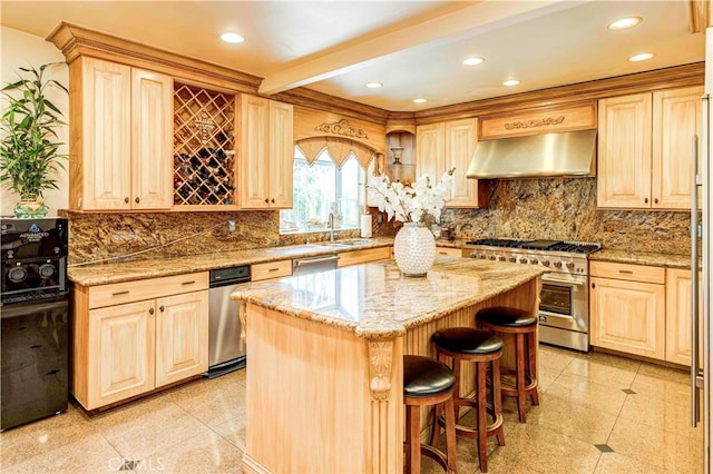 kitchen featuring a center island, range hood, stainless steel appliances, light stone countertops, and light brown cabinetry