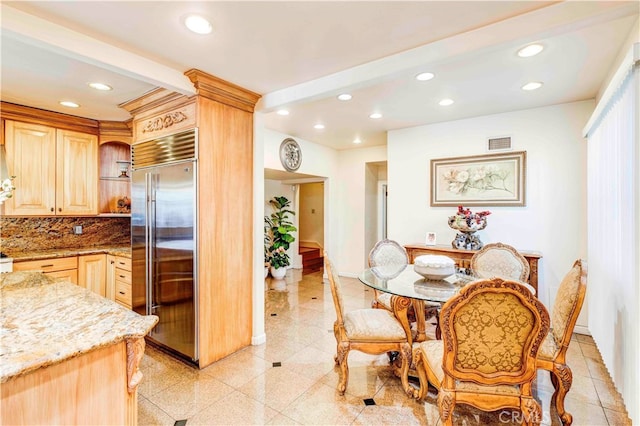 interior space featuring stainless steel built in refrigerator, light brown cabinetry, light stone counters, and tasteful backsplash