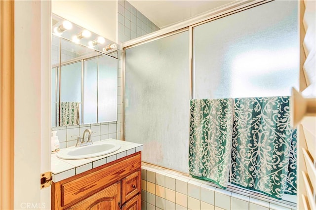 bathroom with tile walls, vanity, and a shower with door