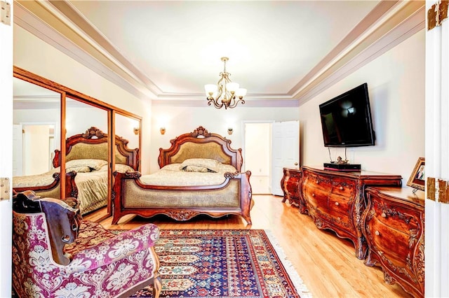 bedroom with a chandelier, a closet, hardwood / wood-style flooring, and crown molding