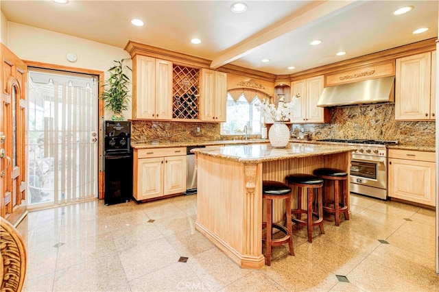 kitchen with light stone counters, a kitchen island, ventilation hood, a breakfast bar, and stainless steel range