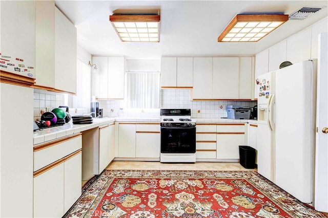 kitchen with decorative backsplash, white cabinets, and white appliances