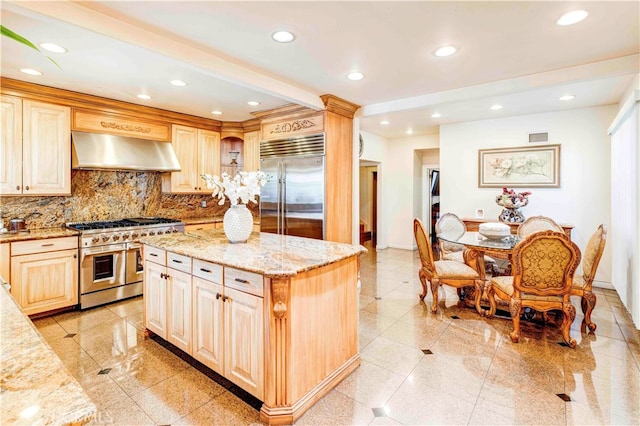 kitchen featuring tasteful backsplash, range hood, a kitchen island, premium appliances, and light stone countertops