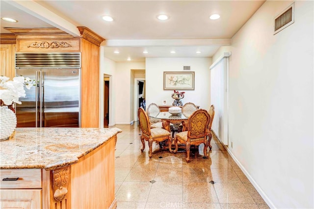 kitchen with stainless steel built in refrigerator, light brown cabinets, and light stone countertops