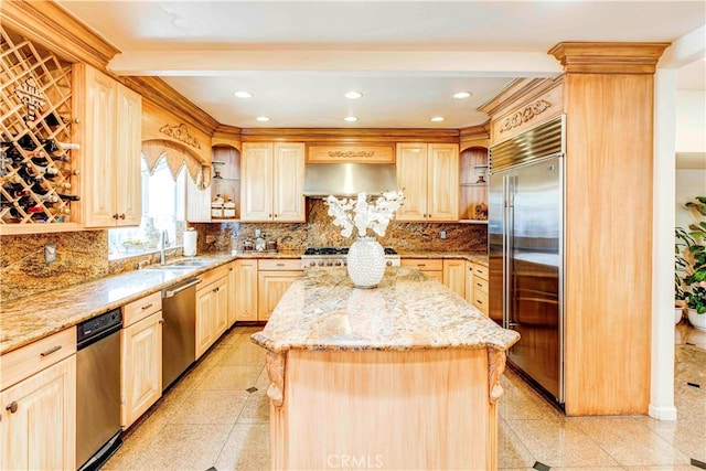 kitchen with a center island, sink, appliances with stainless steel finishes, light stone countertops, and light brown cabinetry