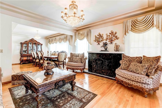 living room with an inviting chandelier, ornamental molding, a high end fireplace, and hardwood / wood-style floors