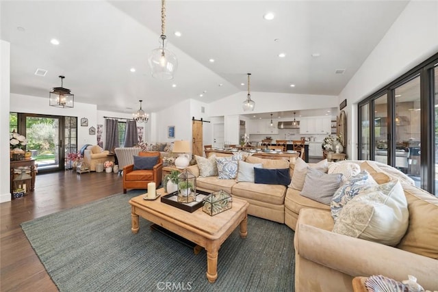 living room with a barn door, dark hardwood / wood-style floors, lofted ceiling, and a notable chandelier