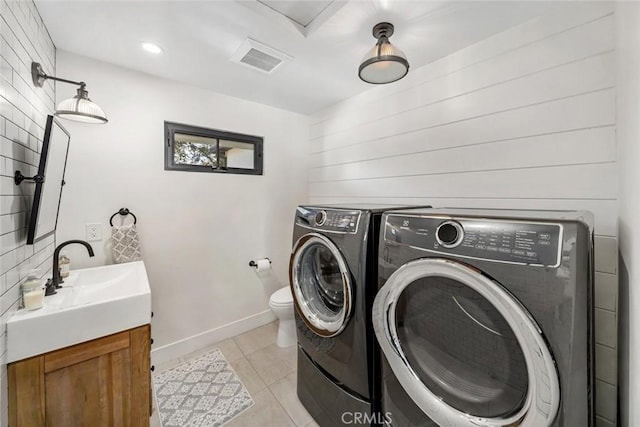 clothes washing area featuring light tile patterned floors, separate washer and dryer, and sink