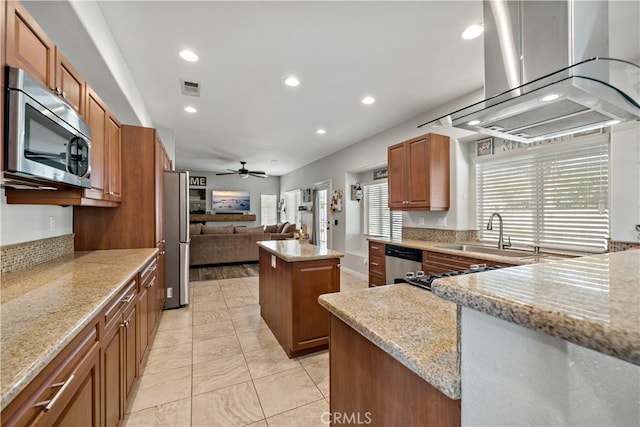 kitchen featuring light stone counters, ceiling fan, sink, a kitchen island, and stainless steel appliances