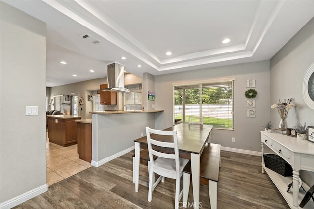 dining area with a tray ceiling and hardwood / wood-style floors