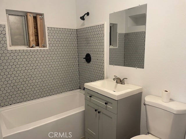 full bathroom featuring vanity, tiled shower / bath combo, and toilet