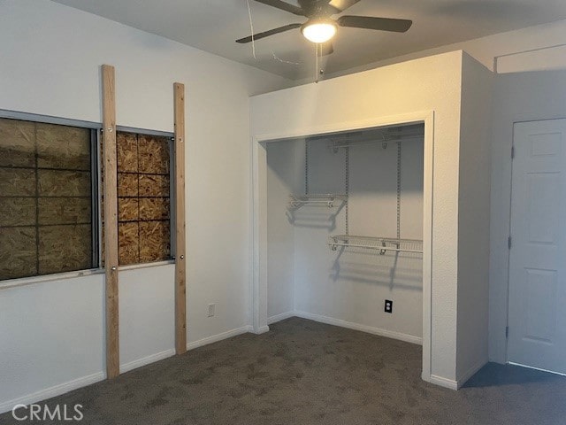 unfurnished bedroom with dark colored carpet, ceiling fan, and a closet