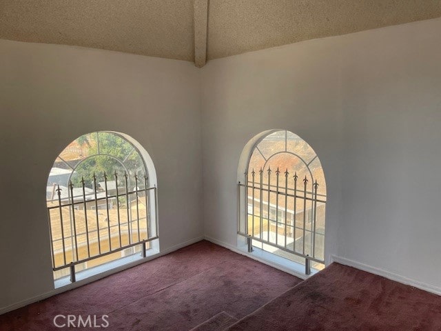 carpeted empty room with a textured ceiling, beamed ceiling, and high vaulted ceiling