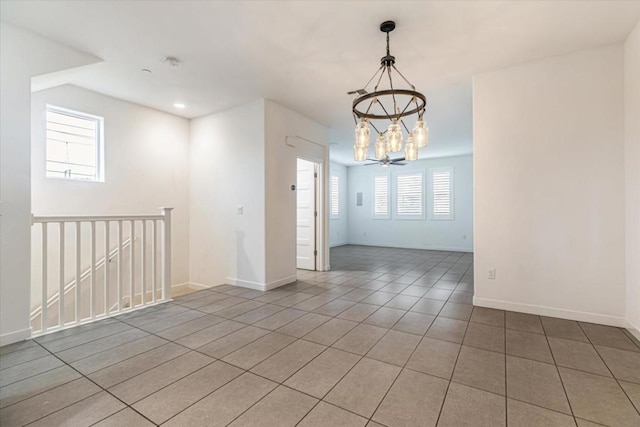 tiled spare room with an inviting chandelier