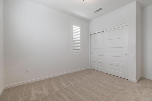 unfurnished bedroom featuring light colored carpet and a closet