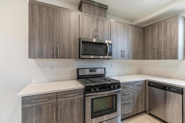 kitchen with stainless steel appliances, dark brown cabinets, light tile patterned floors, and backsplash