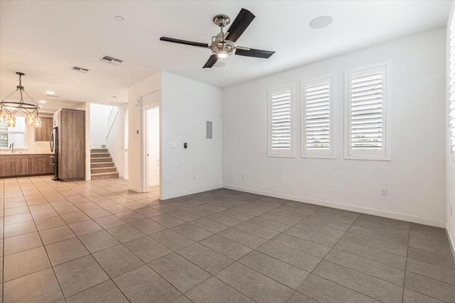 unfurnished living room with ceiling fan with notable chandelier, tile patterned floors, and sink