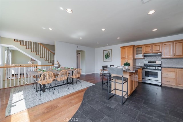 kitchen featuring a kitchen breakfast bar, tasteful backsplash, dark hardwood / wood-style floors, and stainless steel range with gas stovetop