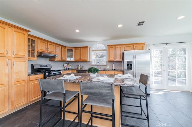 kitchen featuring appliances with stainless steel finishes, a kitchen island, a wealth of natural light, and dark stone counters