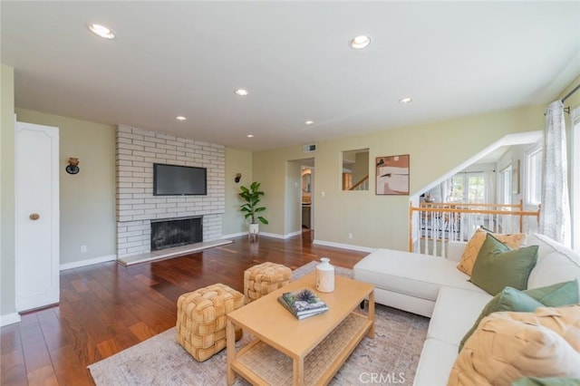 living room with dark hardwood / wood-style flooring and a brick fireplace