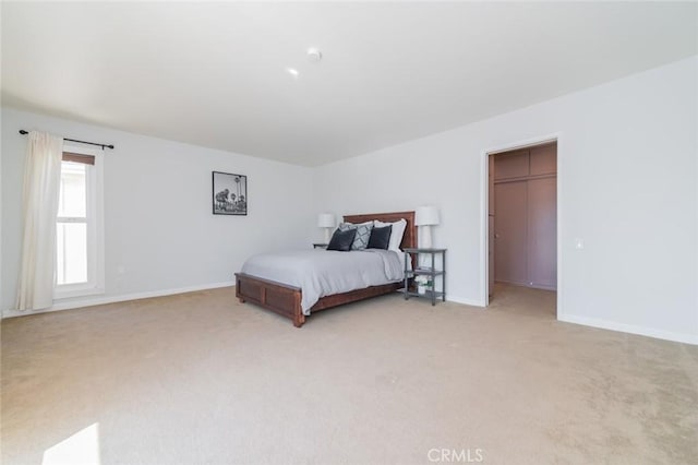 bedroom featuring a walk in closet, light colored carpet, and a closet